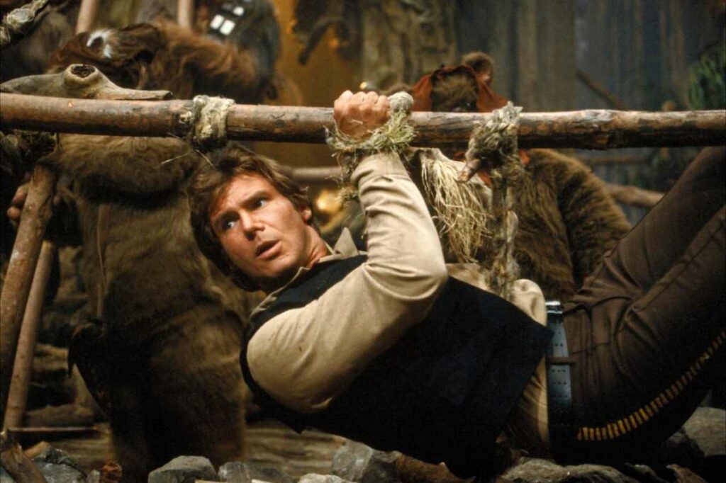 Han Solo suspended over a barbecue pit in Return of the Jedi. An example of Ewoks eating humans, they plan to roast Han for a banquet in C-3PO's honor. (Disney / Lucasfilm)